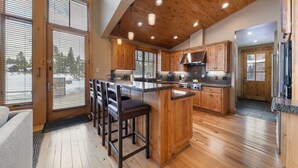 A spacious kitchen with wooden cabinets, a central island, and a bar area with stools.
