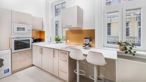 A modern kitchen with built-in appliances, a large window, and a bar area. - Lovely Apartment by National Museum (Budapest)