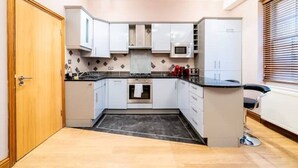A compact kitchen with white cabinets, a microwave, and a stove. - St Paul Cathedral-City of London]London Apartment (London)
