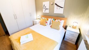 A hotel room with a bed, a nightstand, a wardrobe, and two wall art pieces. - St Paul Cathedral-City of London]London Apartment (London)