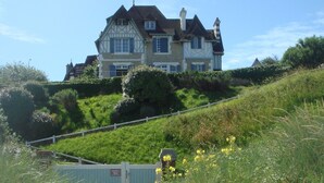 Una grande casa su una collina, con un vialetto lastricato che conduce verso di essa.