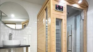 Un baño moderno con sauna de madera, lavabo y espejo.