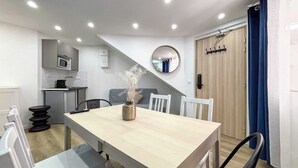 Una cocina moderna con comedor, microondas, pileta y espejo.