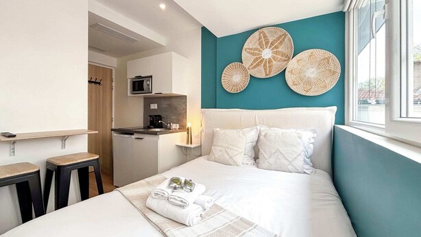 Et moderne hotelværelse med seng, lille tekøkken og udsigt udad.