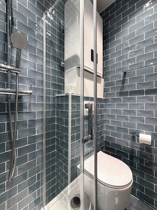 Ein modernes Badezimmer mit einer Glaskabinentrennung zur Dusche, Toilette und Handtuchhalter.