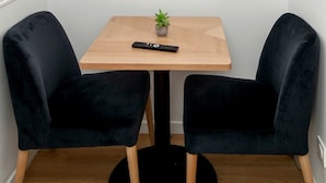 A small dining area with a round table, two black chairs, a small potted plant, and a remote control. - David D Angers 25 - One Bedroom Apartment, Sleeps 2 (Paris)