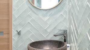 A bathroom with a stone sink, a round mirror, and a small potted plant. - David D Angers 25 - One Bedroom Apartment, Sleeps 2 (Paris)