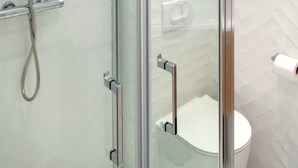 A modern bathroom with a glass-enclosed shower, a toilet, and a glass door. - David D Angers 26 - One Bedroom Apartment, Sleeps 2 (Paris)