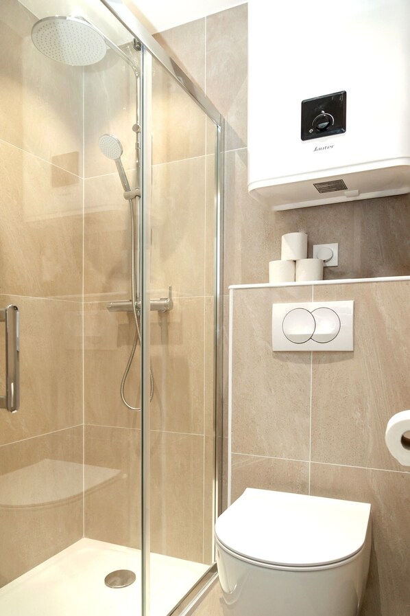 A modern bathroom with a glass-enclosed shower, a toilet, and a wall-mounted air conditioning unit. - David D Angers 22 - Studio Apartment, Sleeps 2 (Paris)