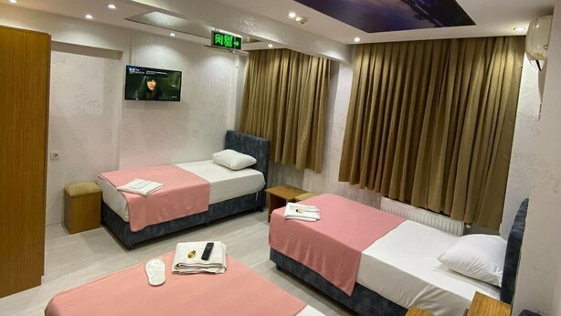 A hotel room with two beds, a ceiling light, a TV, and a mural on the ceiling. - Hotel Diva (Istanbul)