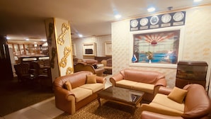 A living room with leather sofas, a coffee table, patterned carpet, a decorative wall, and a clock displaying time in New York, Istanbul, Tokyo, and London. - Hotel Diva (Istanbul)