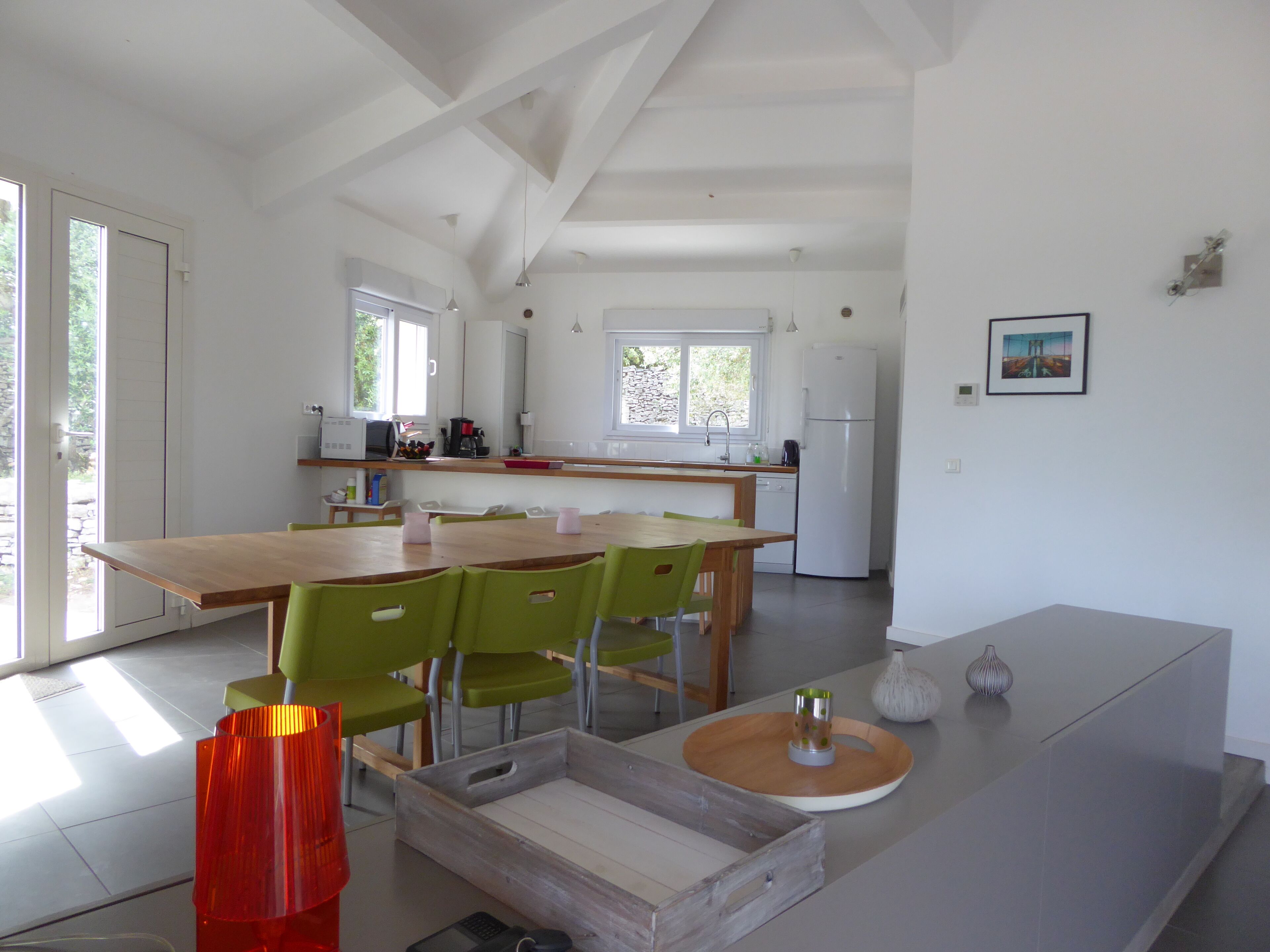 A modern kitchen with a wooden dining table, green chairs, and a white refrigerator.