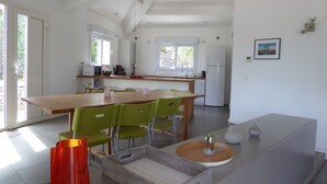 Una cocina moderna con una mesa de comedor de madera, sillas verdes y un refrigerador blanco.