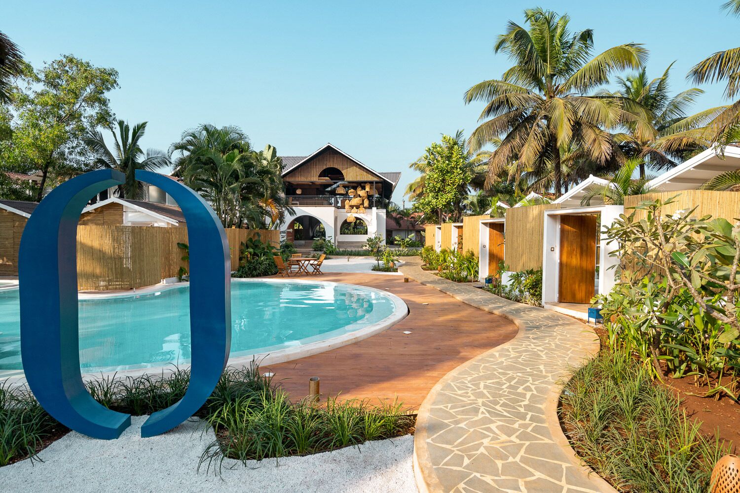 A resort with a swimming pool, palm trees, and a building with a wooden facade.