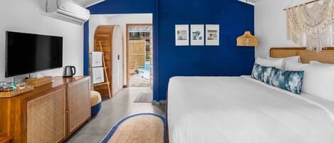 A bedroom with a large bed, a TV, a wooden dresser, and a blue accent wall.