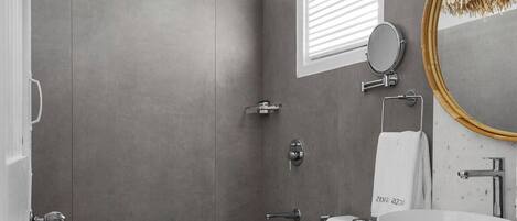 A modern bathroom with a white vanity, a round mirror, and a large round sink.