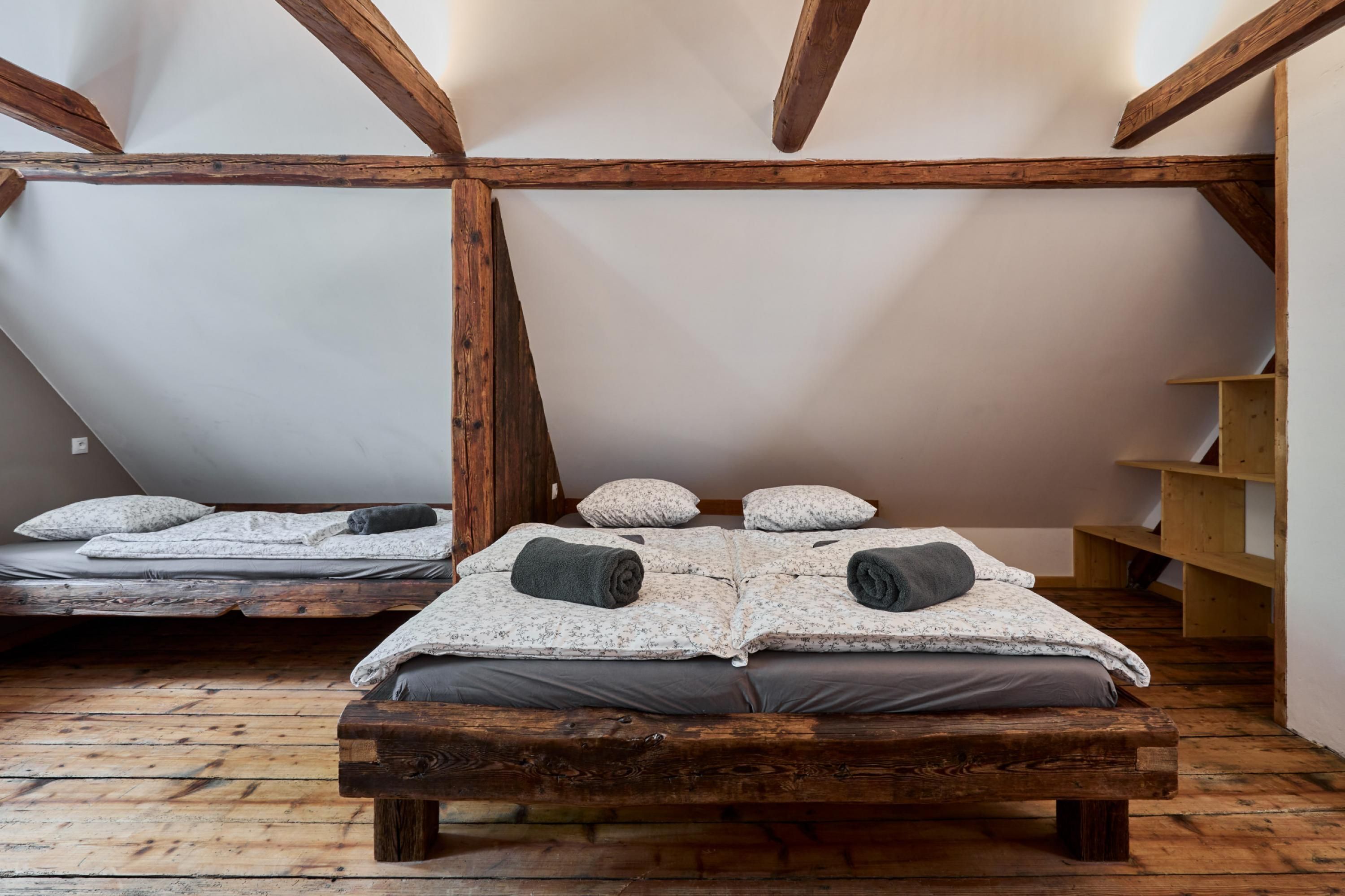 Ein rustikales Zimmer mit zwei Holzbetten, einer Holzbank und einem Holzregal.