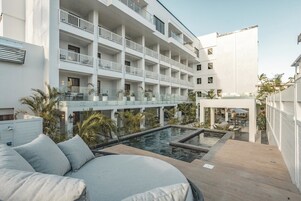 Una piscina al aire libre, sombrillas, sillones reclinables de piscina