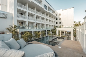 Una piscina al aire libre, sombrillas, sillones reclinables de piscina