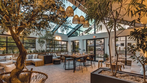 An indoor space with a glass ceiling, seating areas, and a dining table.