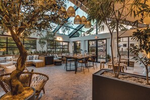 An indoor space with a glass ceiling, seating areas, and a dining table. - Fort George Hotel & Spa (Belize City)