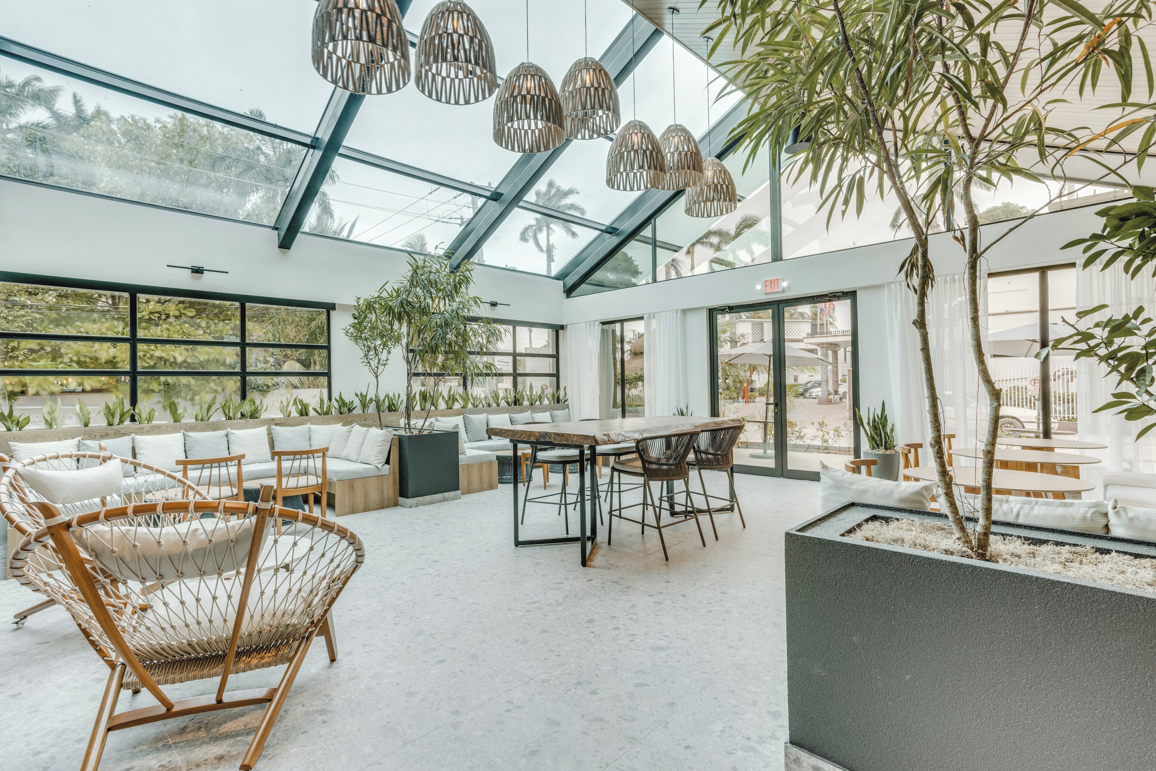 A modern interior with a glass ceiling, wicker furniture, and a dining area.