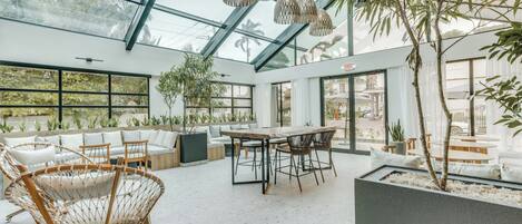 Un interior moderno con techo de vidrio, muebles de mimbre y un comedor.