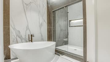 Une salle de bain moderne avec une baignoire sur pieds, une douche en verre et des murs en marbre.