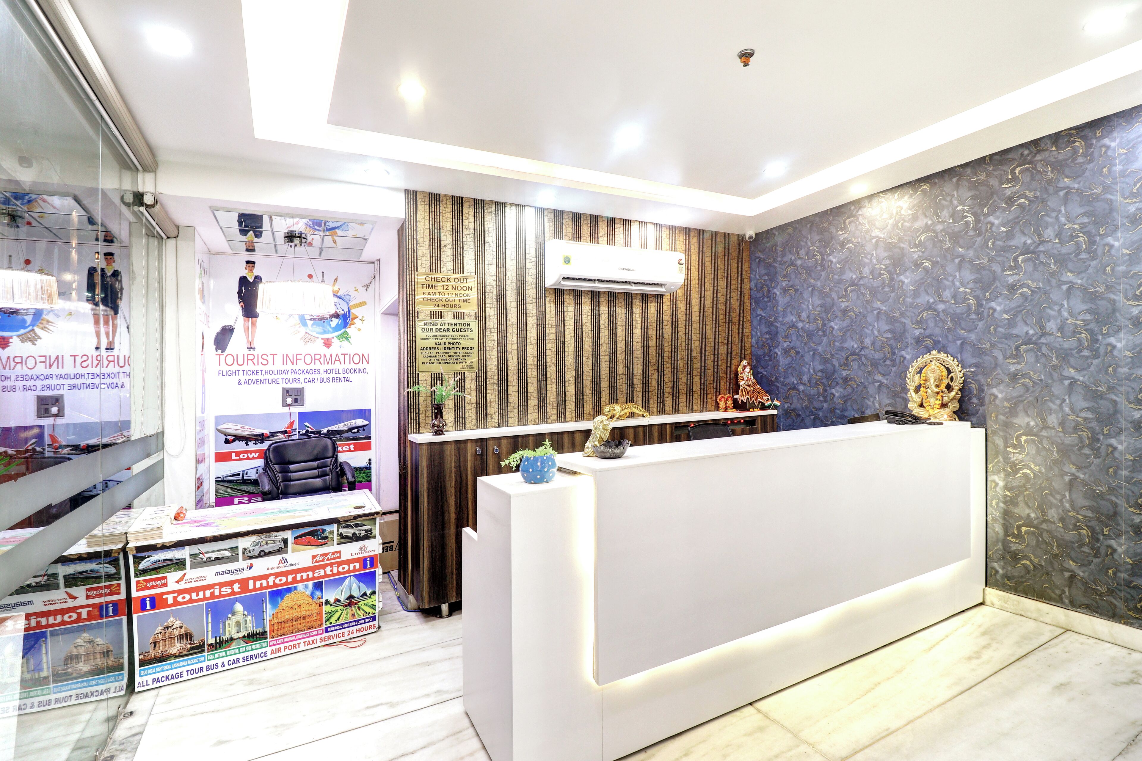 A hotel reception area with a modern design, including a reception desk, air conditioning unit, and informational posters.