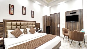 Una camera d'albergo con un letto grande, una TV a parete e un'area salotto con poltrone.