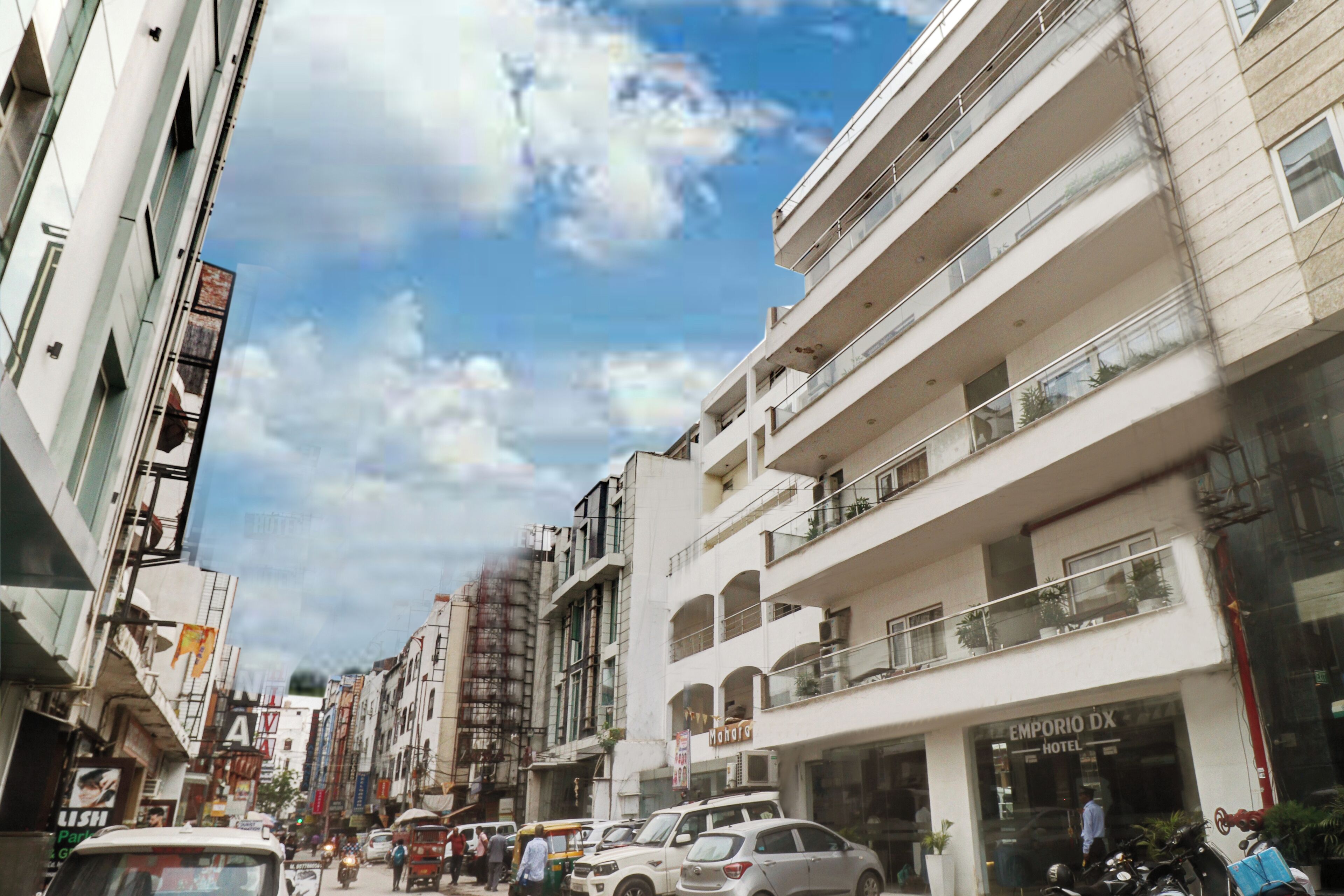 A multi-story hotel with balconies, a visible entrance, and a clear sky.