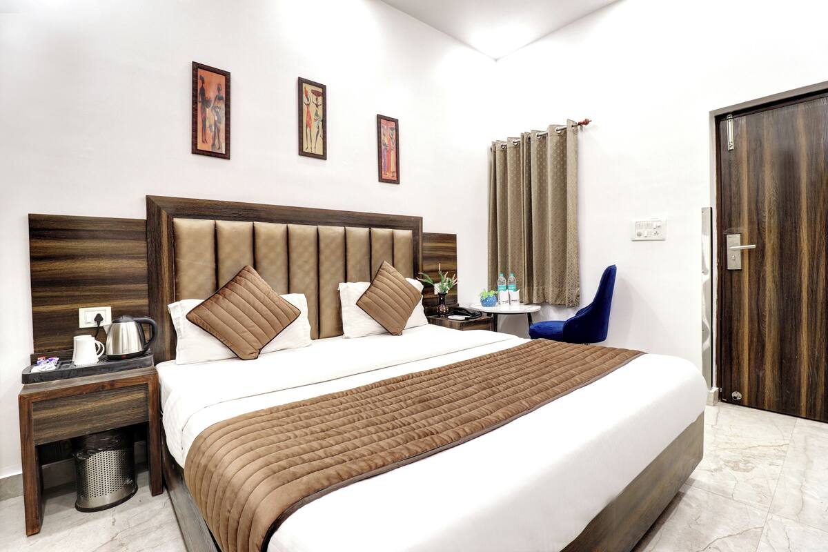 Une chambre d’hôtel avec un grand lit, une table de chevet avec une bouilloire, une chaise et une porte.
