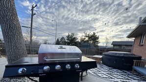 A Char-Broil gas grill with four burners and a stainless steel lid, placed on a concrete patio with a patterned rug. - Hot Tub, Entertainers Lounge, 6 bedrooms - Denver's Beer Inspired BnB (westminster)