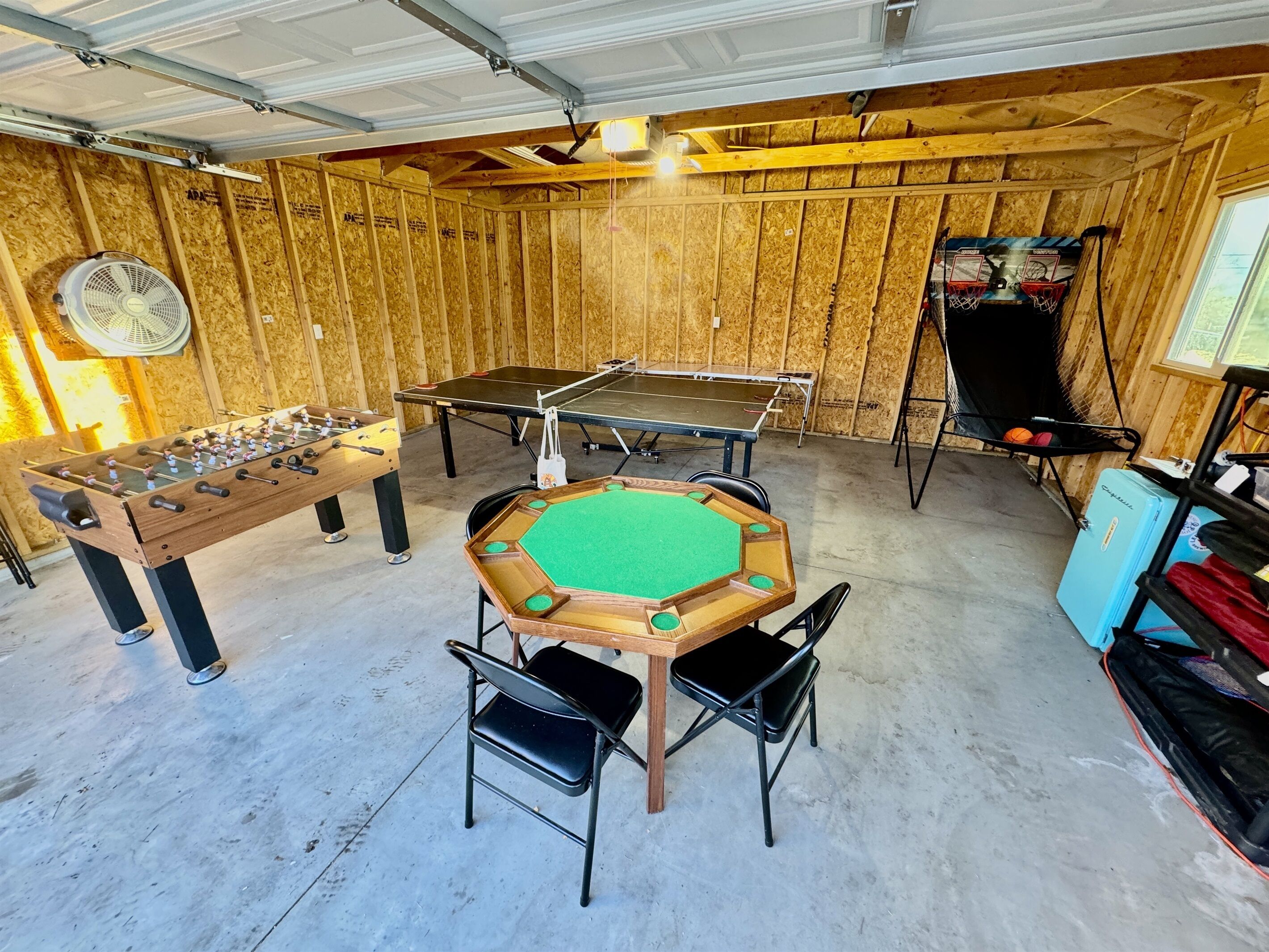 A recreational room with a foosball table, ping pong table, and a pool table.