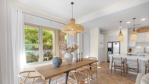 A spacious kitchen with white cabinets, a central island, and a dining area with a wooden table and chairs.