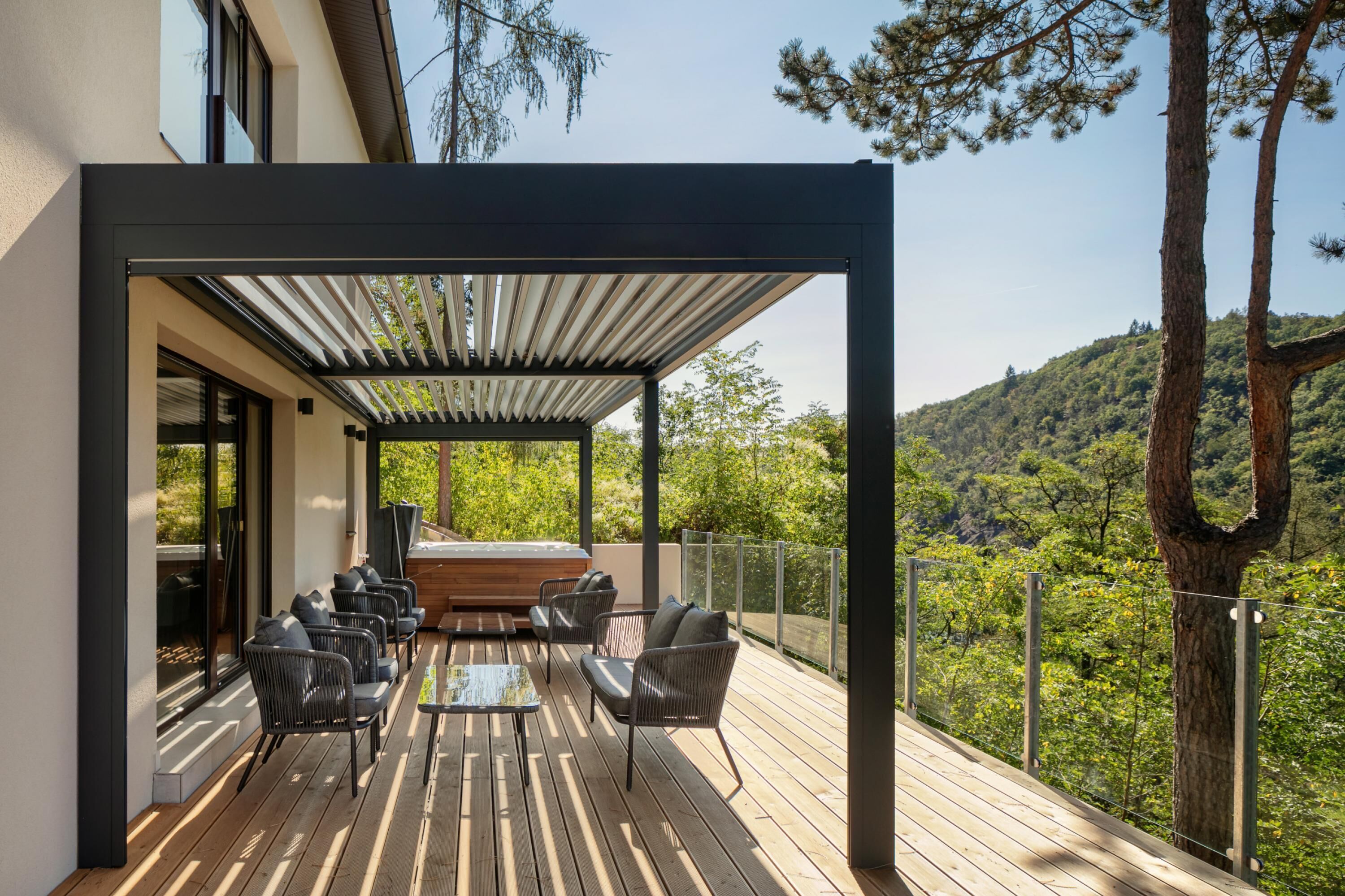 Un espace extérieur abrité avec une terrasse en bois, un banc intégré et des chaises.