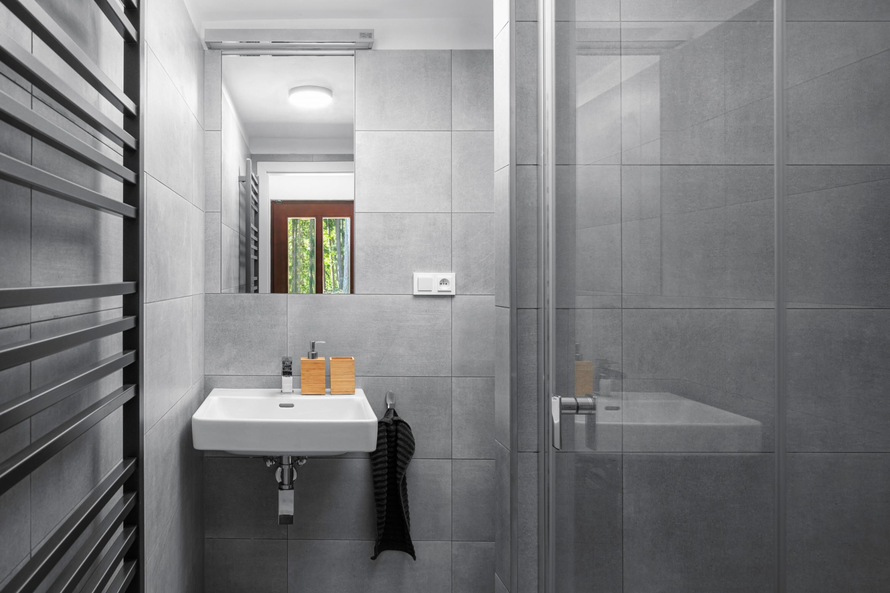 Ein modernes Badezimmer mit einem weißen Waschbecken, einem Spiegel und einer Duschkabine.