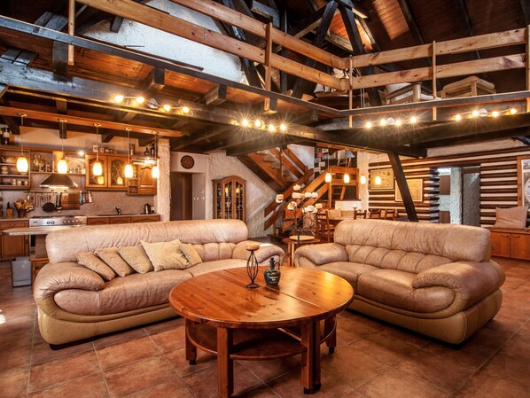 A rustic interior with wooden beams, leather sofas, a wooden coffee table, and a kitchen area. - Benecko Lbs160 in Benecko (Benecko)