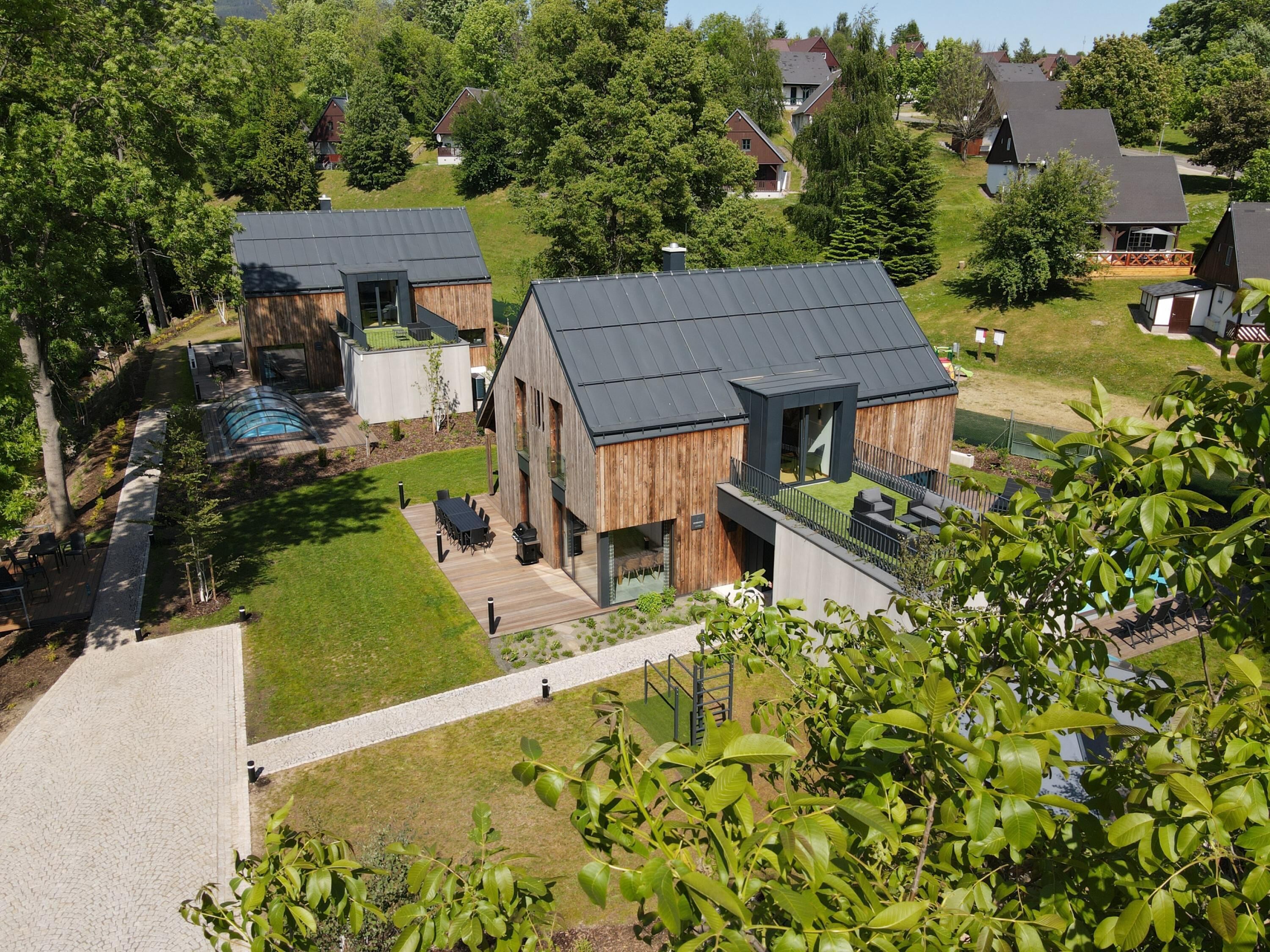 Une maison moderne dotée d’une grande terrasse, d’une piscine et d’une pelouse bien entretenue.