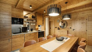 A modern kitchen with wooden cabinetry, a dining table with chairs, and pendant lights. - Cerny Dul Kcml115 in Cern Dul (Cerny Dul)