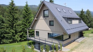 A modern house with a sloped roof, large windows, and a balcony.
