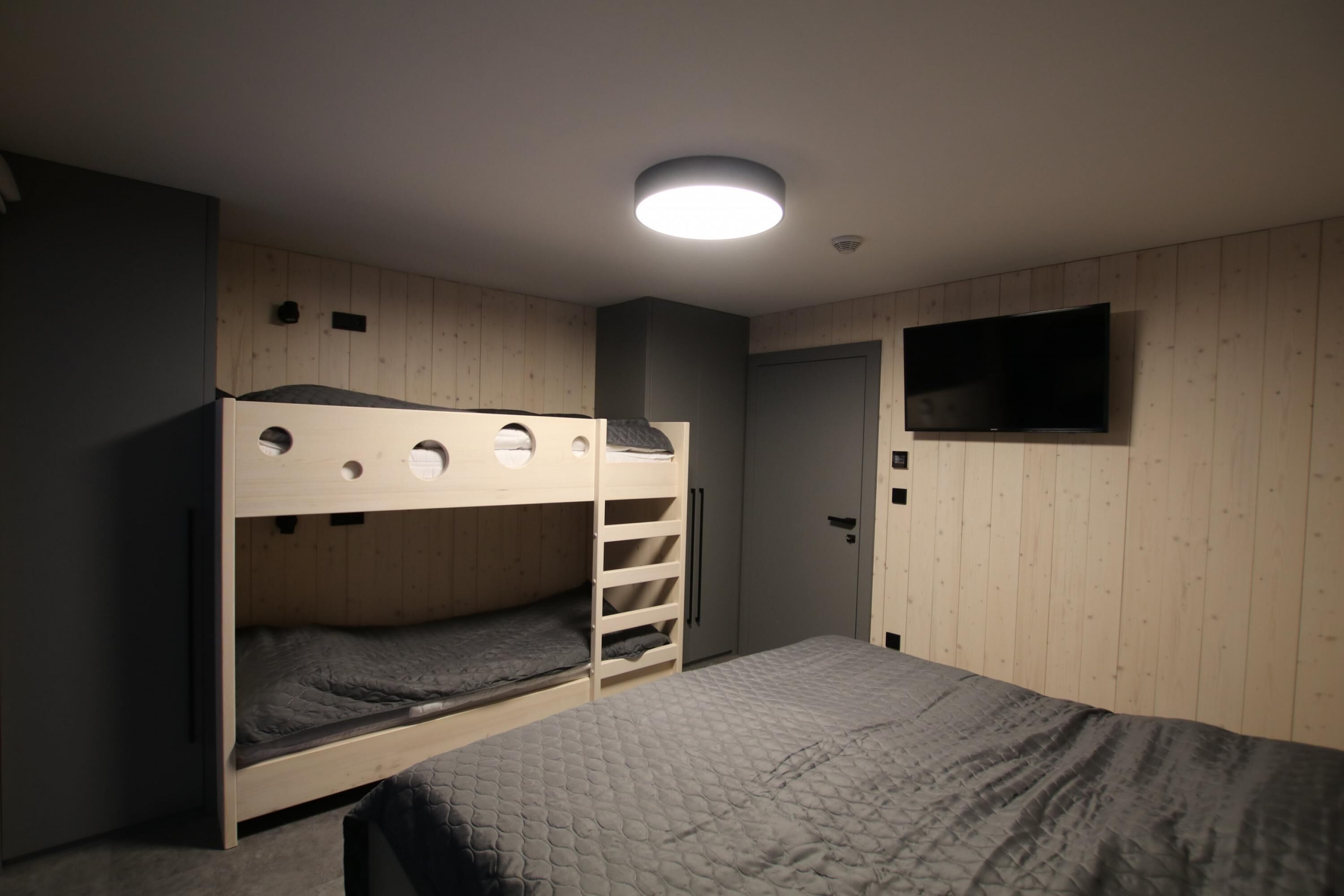 Habitación con literas, un televisor en la pared y una puerta.