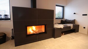 A modern living room with a built-in fireplace, a sofa, and a window with blinds.