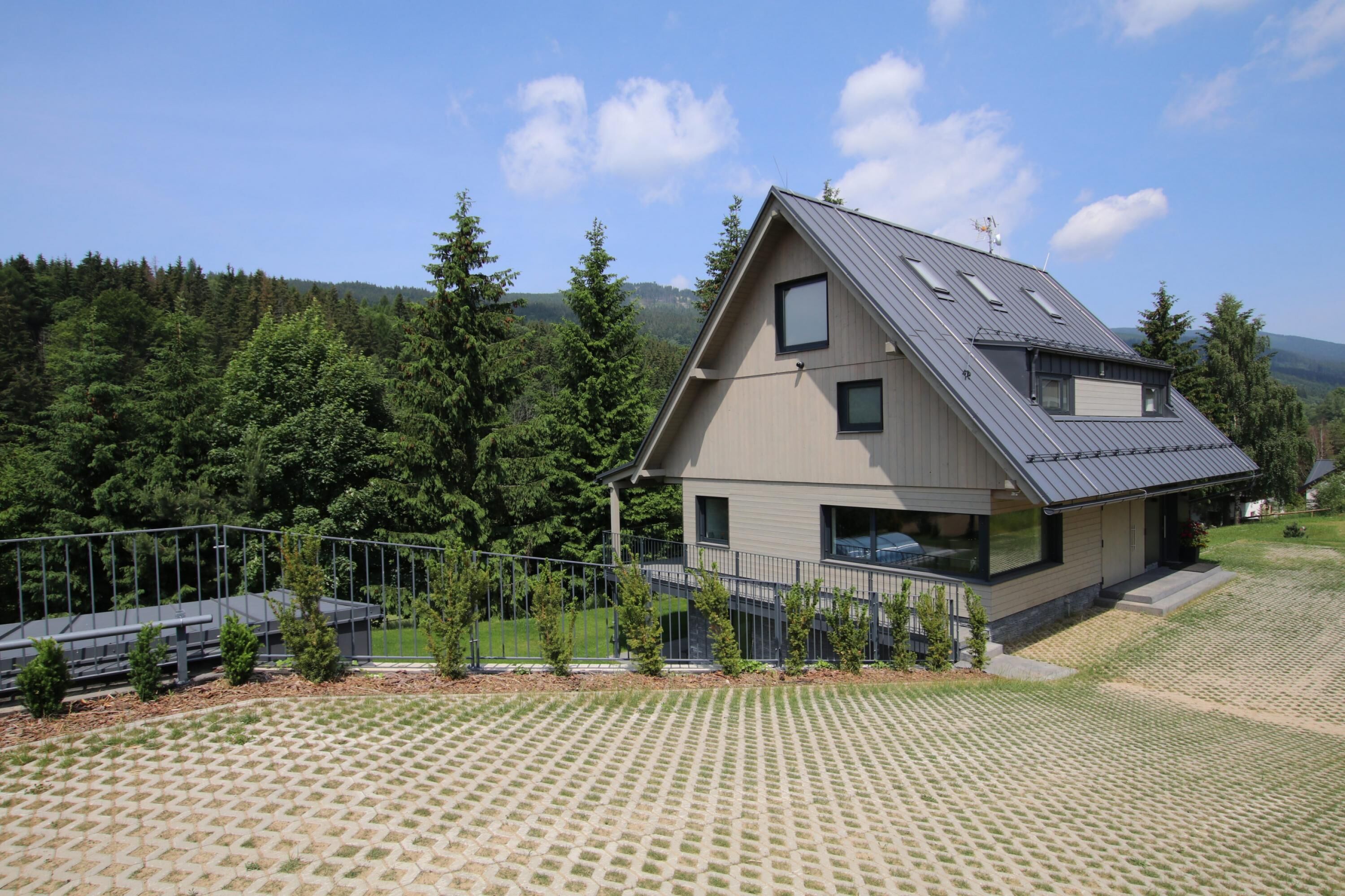 A modern house with a sloped roof, a small balcony, and a paved driveway.
