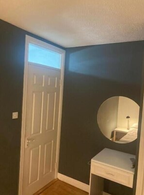 A cozy room with a bedside table, lamp, and mirror.