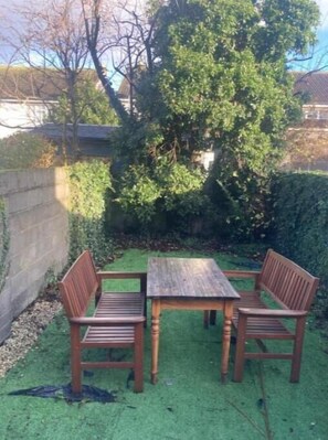 Sit and unwind in this serene outdoor seating area with a table and benches surrounded by lush greenery.