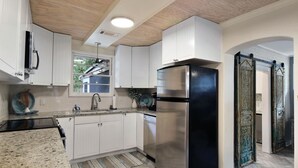 Une cuisine moderne avec des armoires blanches, un réfrigérateur en acier inoxydable et un comptoir en granit.