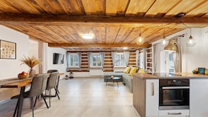 A spacious kitchen with a wooden ceiling, a dining area with a long table and chairs, and a sofa in the living area. - Dolni Branna Kdb026 in Doln Brann (Dolni Branna)