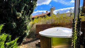 A hot tub in a garden with a wooden deck, surrounded by greenery and a clear sky. - Dolni Branna Kdb026 in Doln Brann (Dolni Branna)