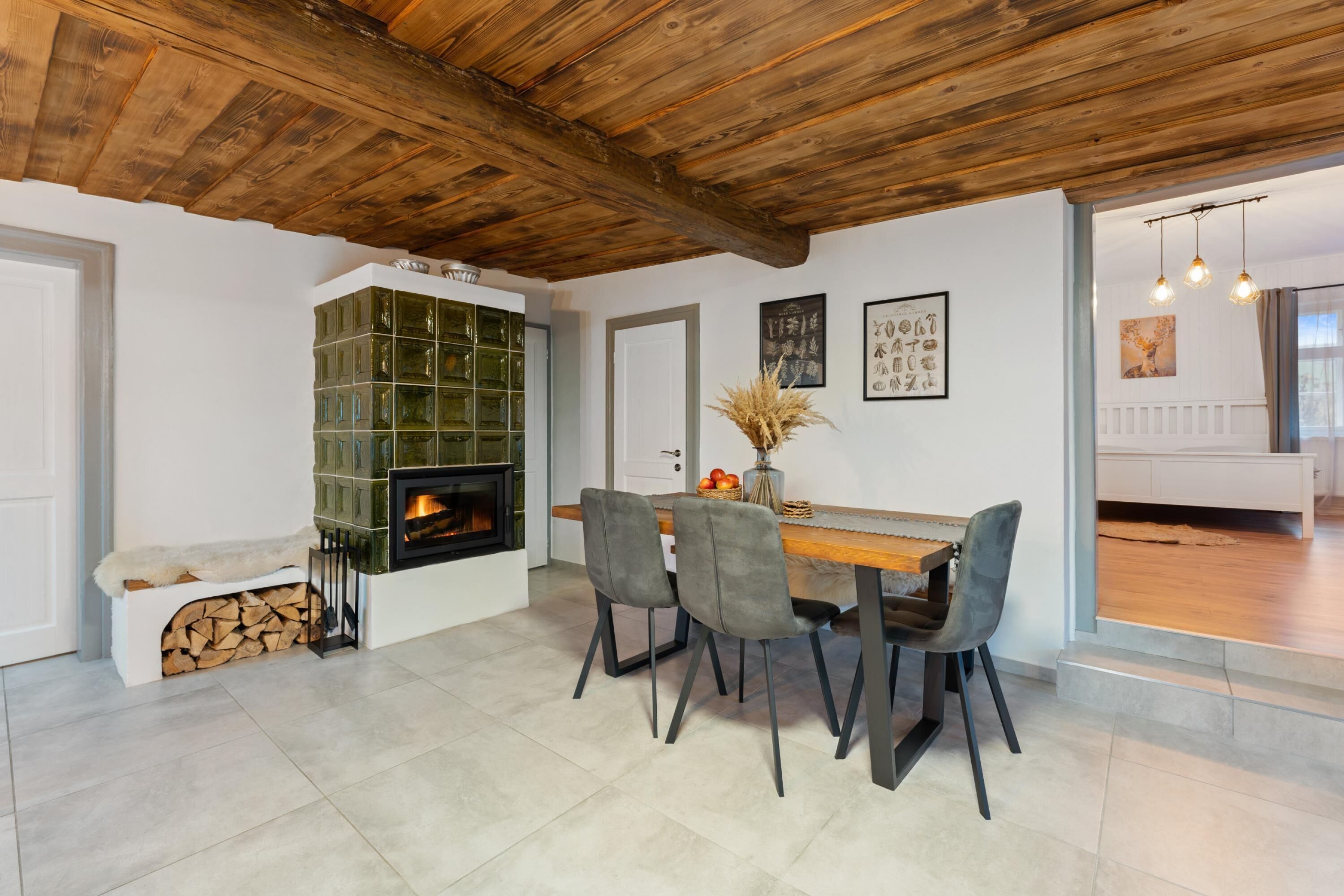 Un comedor con techo de madera, chimenea y una mesa con sillas.